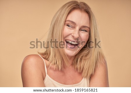 Adult lady in shirt looking away and smiling in studio