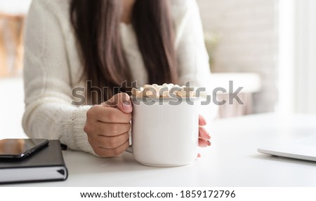 brunette woman holding a cup of marshmallow cocoa