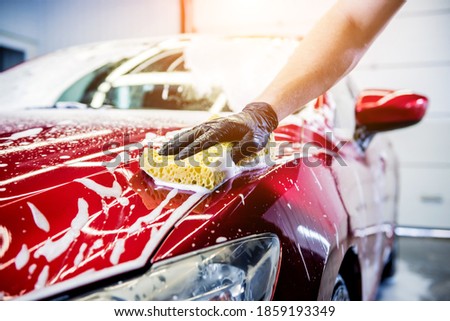 Worker washing red car with sponge on a car wash Royalty-Free Stock Photo #1859193349