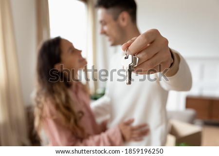 Happy husband and wife renters family. Young couple moving to first home showing keys to new house close up. Tenant, relocation day to own flat, ownership, bank lending, real estate agency ad concept Royalty-Free Stock Photo #1859196250