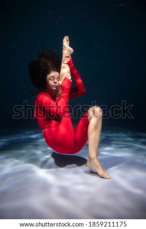 The girl is engaged in yoga under the water in sports clothes. Immersion in Meditation