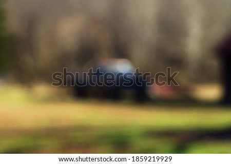 A purposefully blurry background of an old truck parked in a shadowy yard. Royalty-Free Stock Photo #1859219929