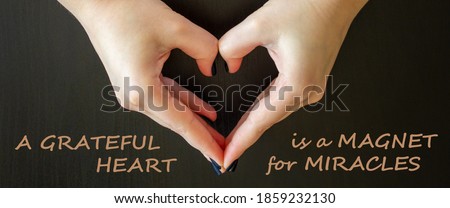 Inspirational motivational quote - A grateful heart is a magnet for miracles,with woman making heart shape on dark background. Heart shape, Symbol of love, The manifestation of love. Concept.