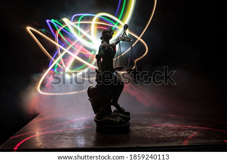 Law concept. Miniature colorful artwork decoration with fog and backlight. The Statue of Justice - lady justice or Iustitia / Justitia the Roman goddess of Justice. Selective focus