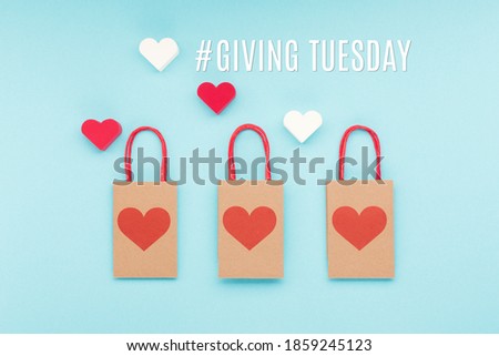 Giving Tuesday, global day of charitable giving after Black Friday shopping day. Charity, give help, donations support concept with text message, red  heart and shopping bags on blue background.
