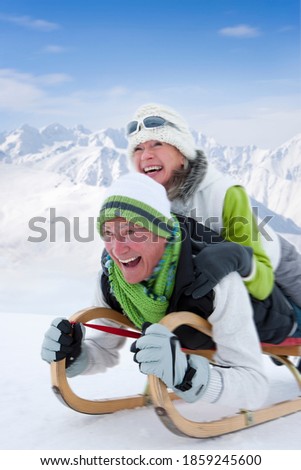 Close up of a senior couple sledding down the snowy slope at full speed with motion blur