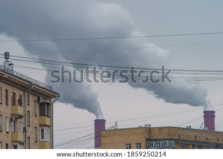 Heat station pipes, smoke. Smoking pipes, gray smoke with gray gloomy winter sky as background. Chimneys, concept of industry and ecology, heating season, global warming