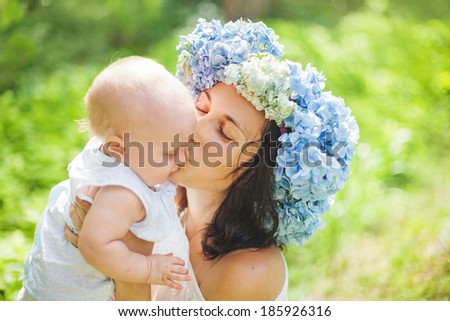 mother wearing wreath with her sweet baby daughter in sunny summer day
