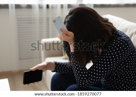 Close up unhappy frustrated Asian woman holding white empty mock up plastic card and phone, touching head, crying, having problem with credit card, loss money, internet fraud and scam concept Royalty-Free Stock Photo #1859270077