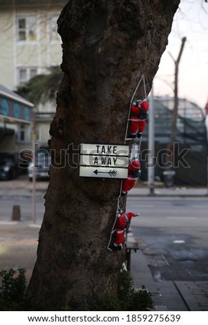 3 toy santa clauses climbing onto the trunk of a brown tree and the word "take away" on the same tree