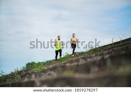 Athletic couple running marathon on stairs. Workout in urban outdoor. Jogging people training outside.