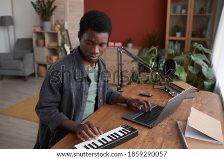 Portrait of young African-American man composing music in home recording studio, copy space