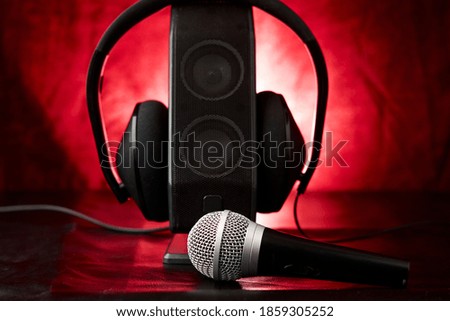 Microphone accompanied by a single speaker with large earphones, backlit diffuse background