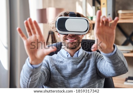 Close up portrait of the handsome unshaven man wearing virtual reality headset stretching arms to the camera while testing new application with pleasure smile