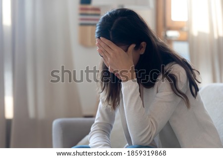 Enough from me... Frustrated depressed young woman or teenager sitting on couch at home crying covering face with palm feeling bad exhausted tired, suffering of loneliness headache crisis in relations Royalty-Free Stock Photo #1859319868