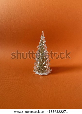 Glass pine tree on orange background. Minimal composition.