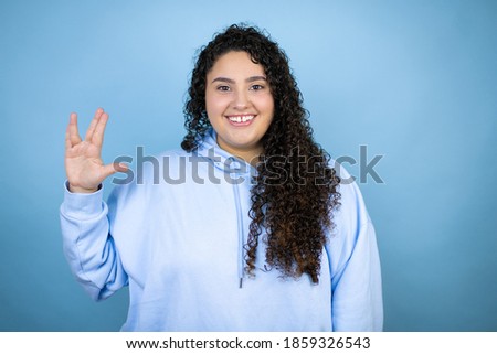 Young beautiful woman wearing casual sweatshirt over isolated blue background doing hand symbol