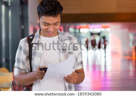 A close up shot of a happy student using his phone after receiving his test results. Royalty-Free Stock Photo #1859342080