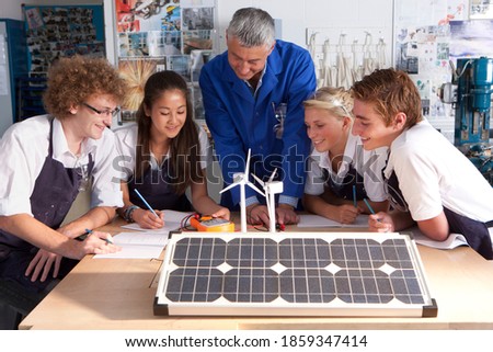 A medium shot of a teacher talking to young students about wind power and solar panels in a vocational school. Royalty-Free Stock Photo #1859347414