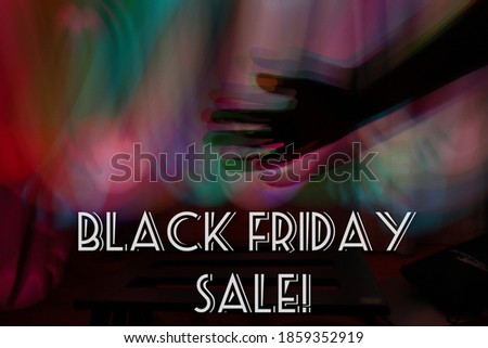 Black friday sale written poster with abstract conceptual silhouette hand in front of long exposure various colorful lights 