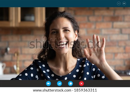 Overjoyed young beautiful caucasian sincere woman making hello hi gesture, looking at camera, starting distant online conversation with friends, computer software video call application screen view. Royalty-Free Stock Photo #1859363311