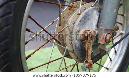 Front wheel hub and motorcycle spokes. Old vintage motorcycle with peeling paint and rust in vintage style. Close focus and select an object