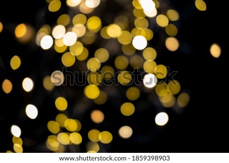 Blurred abstract gold glitter texture, defocused christmas lights on black background. Holiday christmas concept.