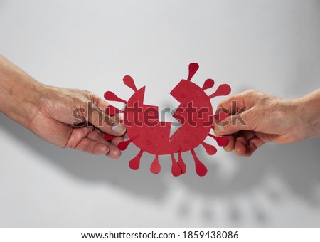 End of coronavirus concept. Hands holding representation of destruction and end of the coronavirus made from paper on white background. Cured of coronavirus (covid-19) and end of quarantine concept.