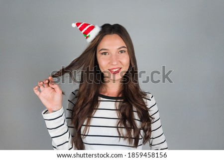 A happy young woman with Christmas decoration in her hair looks into the camera. Celebrating Christmas and New Year. High quality photo