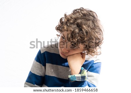 portrait of a young boy boring. Child with head resting on fist. Kid bored at home during the coronavirus pandemic.