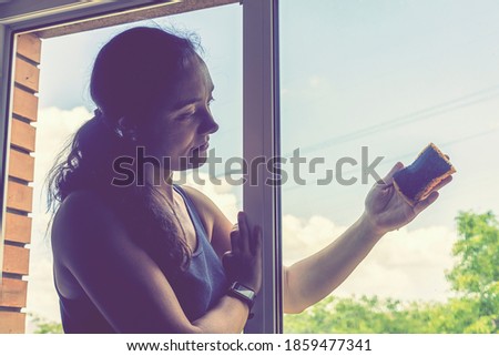 Back view of the young woman who washing the window with rag and window cleaner in the room. Cute girl with long hair washes a glass with detergent. toned. selected focus. toned