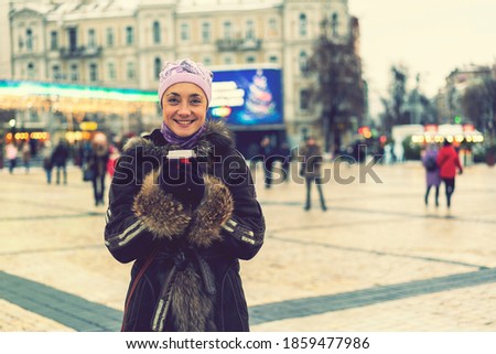 Beautiful young woman with coffee cup in the city. Beautiful woman with coffee on the street in winter clothes. Woman Having Hot Drink Outdoors On Winter Market. toned
