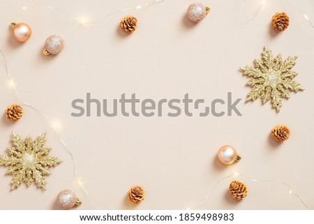 Elegant Christmas flat lay composition. Golden snowflakes, balls, cones, garland on pastel beige background. Minimal, nordic style. Christmas greeting card mockup.