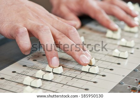 close-up hands of sound engineer work with faders on mixer
