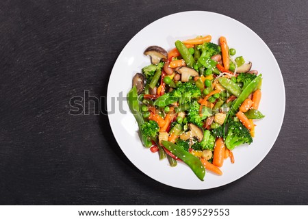 plate of stir fried vegetables on dark background, top view Royalty-Free Stock Photo #1859529553
