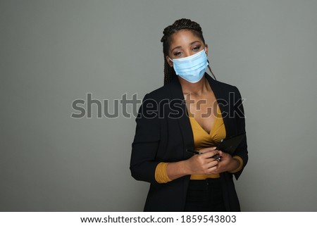 Portrait of an African American woman in business suit wearing face mask isolated on gray copy space