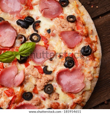 Homemade pizza with black olives, tuna and italian ham
