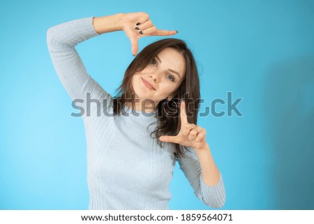 Happy woman making frame with fingers isolated on a blue background