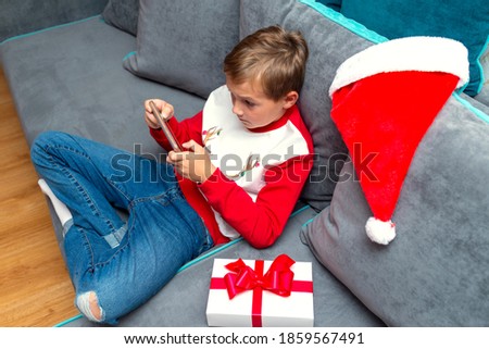 Top view Attractive kid boy using smartphone on Christmas holidays white gift for xmas photo at home