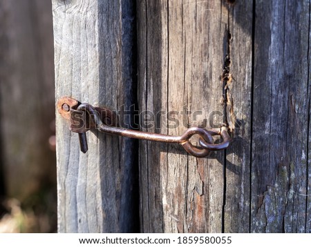 safety in the old days. old gray door locked on a metal hook. Closeup photo