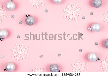 Top view of Christmas background made of silver decorations  balls and white snowflakes over pastel pink. Happy New Year greetings. Festive winter holidays backdrop. Flat lay. Copy space.