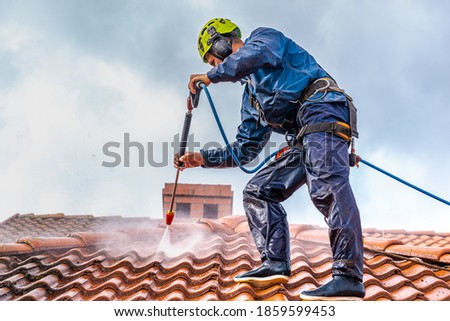 worker washing the roof with pressurized water Royalty-Free Stock Photo #1859599453