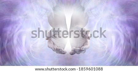 Sending you pure unconditional love and spiritual healing energy - female cupped hands emerging from an angelic pale lilac ethereal  energy background 
