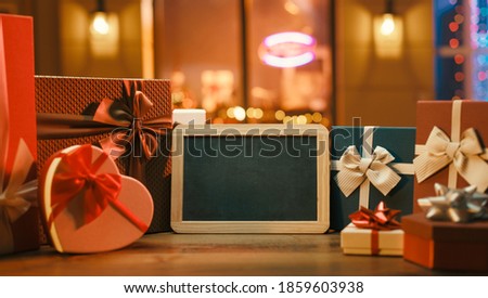 Christmas gifts shopping and blank chalkboard, open stores in the background