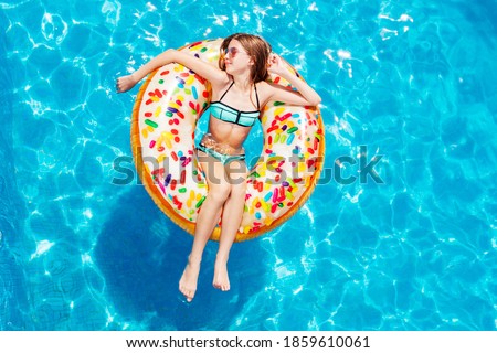 View from above of happy teen girl swim on inflatable yellow ring with in relaxed position