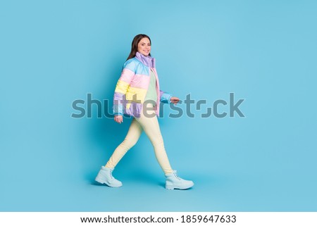 Full length profile photo portrait of walking girl isolated on pastel blue colored background