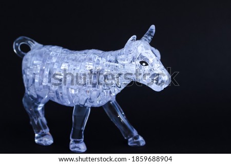 Figurine of a bull from three dimensional puzzles on black background. Symbol of coming New Year 2021, business, stock exchange, finance.
