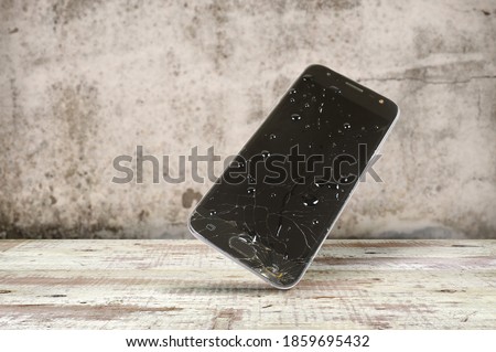 Wet smartphone covered with water drops  falling and crashing on wooden surface with blurred grunge background, Accident with a smartphone