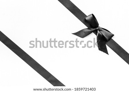 Festive black ribbon with bow isolated on white. Top view, copy space