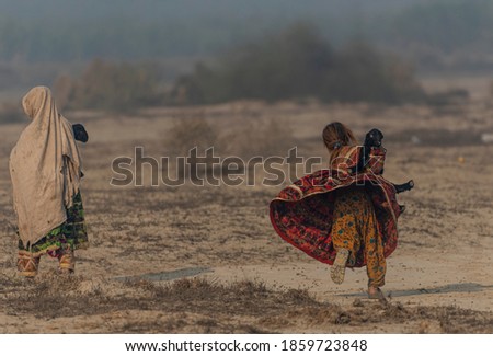 cute little shepherdess with cute 
 new born goat in fields,
nomadic life of shepherds traveling with sheep in the the dust